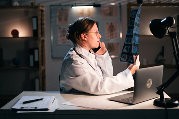 Doctor woman searching x ray scan talk medical diagnosis with patient, working late night in hospital. Physician exam results