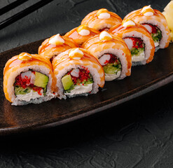 Sushi rolls served on a dark plate with a glossy finish
