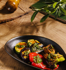 Grilled vegetables with pesto sauce on a wooden table at a rustic setting