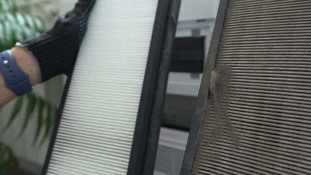 A gloved technician shows the old and new air filters. Replacing the air filter in the air purification system.