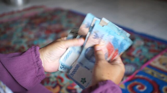 Hands counting fifty thousand rupiah banknotes while conducting financial transactions