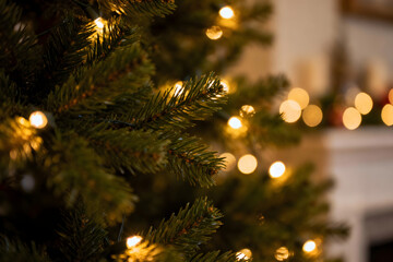 Close up of a festive christmas tree with green pine needles and warm glowing string lights