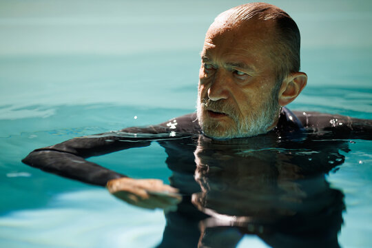 Portrait of diver in wetsuit and neck weight standing in pool 