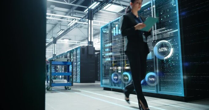  Female IT Professional Walks Through Hyperscale Data Center, Monitoring Tablet Readouts While Animated Infographics Overlay Glass Server Racks, Visualizing Cloud Capacity