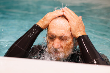 Senior diver splashing water at poolside 