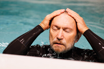 Senior diver in wetsuit swimming in pool 