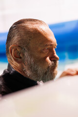 Portrait of senior diver in swimsuit breathing at poolside 