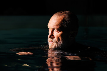 Portrait of senior free diver standing in swimming pool 