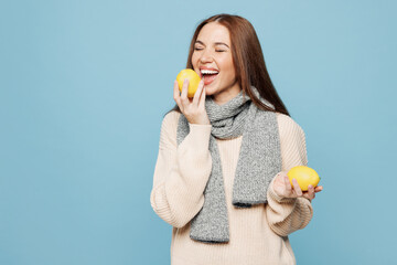 Young smiling happy woman she wear pink sweater scarf hold in hand eat bite lemon isolated on plain...