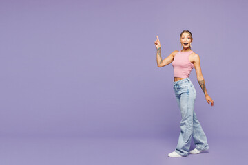 Full body young shocked surprised happy woman wear pink tank top casual clothes walk go point index...