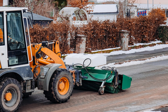 Street sweeper tractor cleaning snowy road