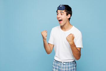 Calm young man he wears pyjamas jam sleep eye mask rest relax at home doing winner gesture...