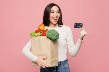 Young shocked surprised woman wears white casual clothes hold brown craft bag for takeaway mock up...