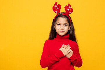 Merry little girl wear red clothes fun decorative deer horns on head posing put folded hands on...