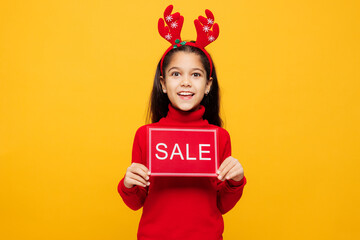 Merry little girl wears red clothes fun decorative deer horns on head posing hold card with sale...