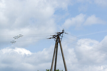 Słup elektryczny na tle zachmurzonego nieba, beton, metal druty elektryczne.	
