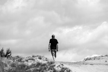 Czarno białe ujęcie sylwetka mężczyzny stojącego na wydmach i patrzącego w dal .