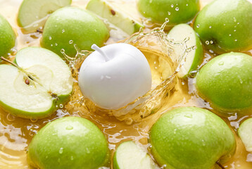 White artificial apple falling into yellow juice splash among fresh green apples