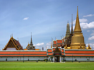 The Grand Palace complex with golden spires and green lawn in Bangkok, Thailand, July 2019