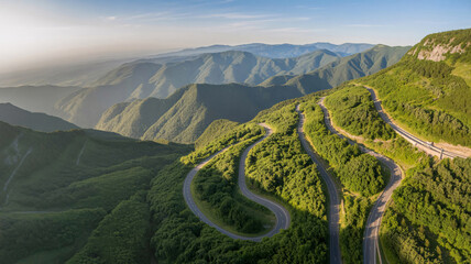 Winding mountain road passing through a green forest under a clear blue sky