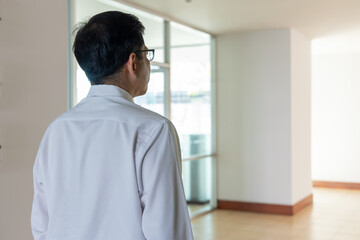 Back or rear view of South East Asian office worker, business man walking in to the office, opening the door