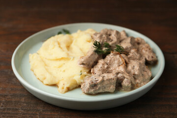 Delicious beef stroganoff with mashed potatoes and thyme served on wooden table, closeup
