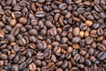 Closeup roasted coffee beans texture showing glossy medium-dark roast, warm brown tones and subtle oil sheen creating cozy breakfast mood for packaging and lifestyle branding