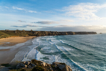 Vue depuis les hauteurs de Pen Hat &agrave; Camaret-sur-Mer, avec les vagues de la mer d&rsquo;Iroise, les falaises et la plage illumin&eacute;e par une lumi&egrave;re douce.