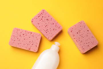 Kitchen sponges and dish soap on yellow background, flat lay