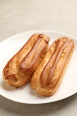 Fresh tasty eclairs on light table, closeup