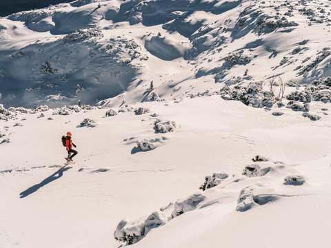 A person snowshoeing in a snowy mountain landscape on a sunny day. Paganella, Roda refuge,Trentino, Italy