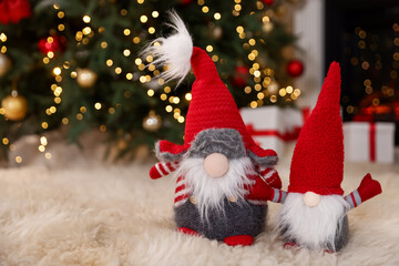 Funny Christmas gnomes on fluffy rug in decorated room. Space for text