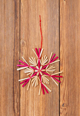 Straw star on wooden background. Christmas tree decoration made of straw.