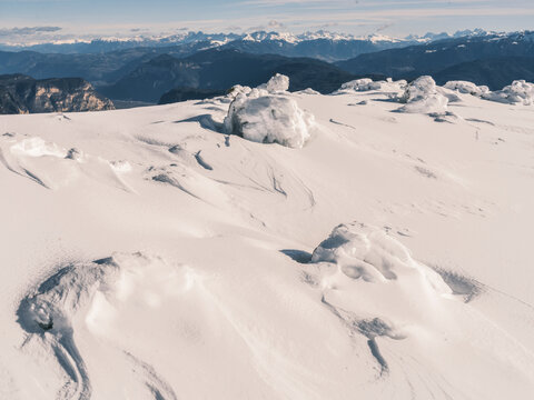 Snow-covered landscape with distant mountains under a blue sky. Paganella, Roda refuge,Trentino, Italy