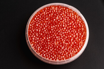 Red Salmon Roe (Ikura) in Plastic Container on Black Background