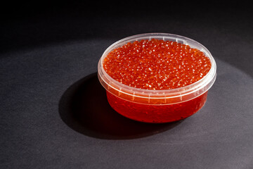 Red Salmon Roe (Ikura) in Plastic Container on Black Background