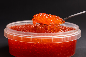 Red Salmon Roe (Ikura) in Plastic Container on Black Background