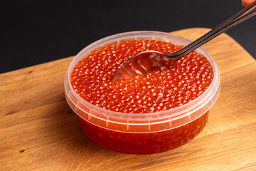 Red Salmon Roe (Ikura) in Plastic Container on Black Background