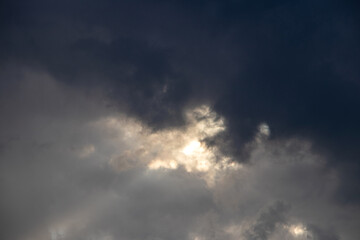 Dramatic landscape of a cloudy sky as a ray of sunlight breaks through dark gray storm clouds
