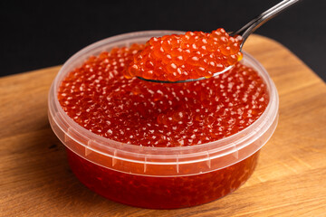 Red Salmon Roe (Ikura) in Plastic Container on Black Background