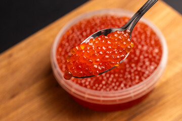 Red Salmon Roe (Ikura) in Plastic Container on Black Background