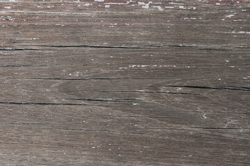 A richly textured, close-up view of distressed wood. The deep gray-brown planks feature prominent grain patterns and natural cracks, giving a rustic, time-worn feel.