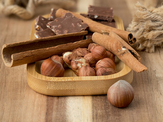 Hazelnuts, cinnamon, chocolate with nuts, background, Christmas wallpaper on a wooden countertop, close-up view, healthy unsaturated fats, spices, plant protein, fiber, vitamins and minerals
