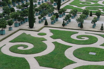 Parterre and rows of shrubs in containers in a formal garden