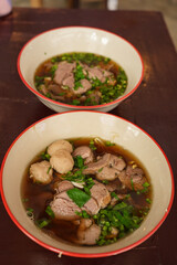 The closed up of Thai noodles. Asian noodle soup with beef meatball with fresh vegetable on wood table. 