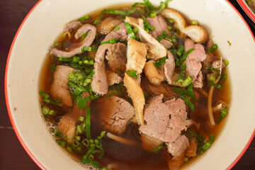 The closed up of Thai noodles. Asian noodle soup with beef meatball with fresh vegetable on wood table. 