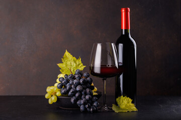 Naklejka premium Red wine bottle with a glass and basket of fresh grapes
