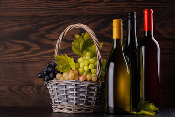 Naklejka premium Red and white wine bottles with a glass and basket of fresh grapes
