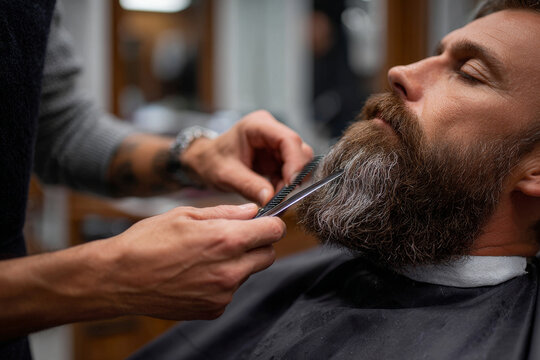 A barber carefully trims a customer's beard, capturing a moment of precision and grooming expertise.