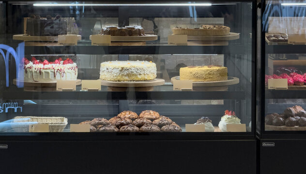 Delicious cakes and pastries fill the bakery display, tempting customers in the afternoon light